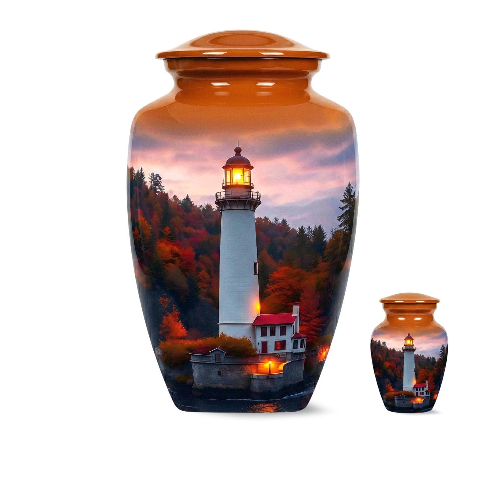A large and a small cremation urn, both featuring a cylindrical shape with a rounded lid. The surface displays a printed scene of a white lighthouse with a glowing lantern room, set against a backdrop of autumn trees and